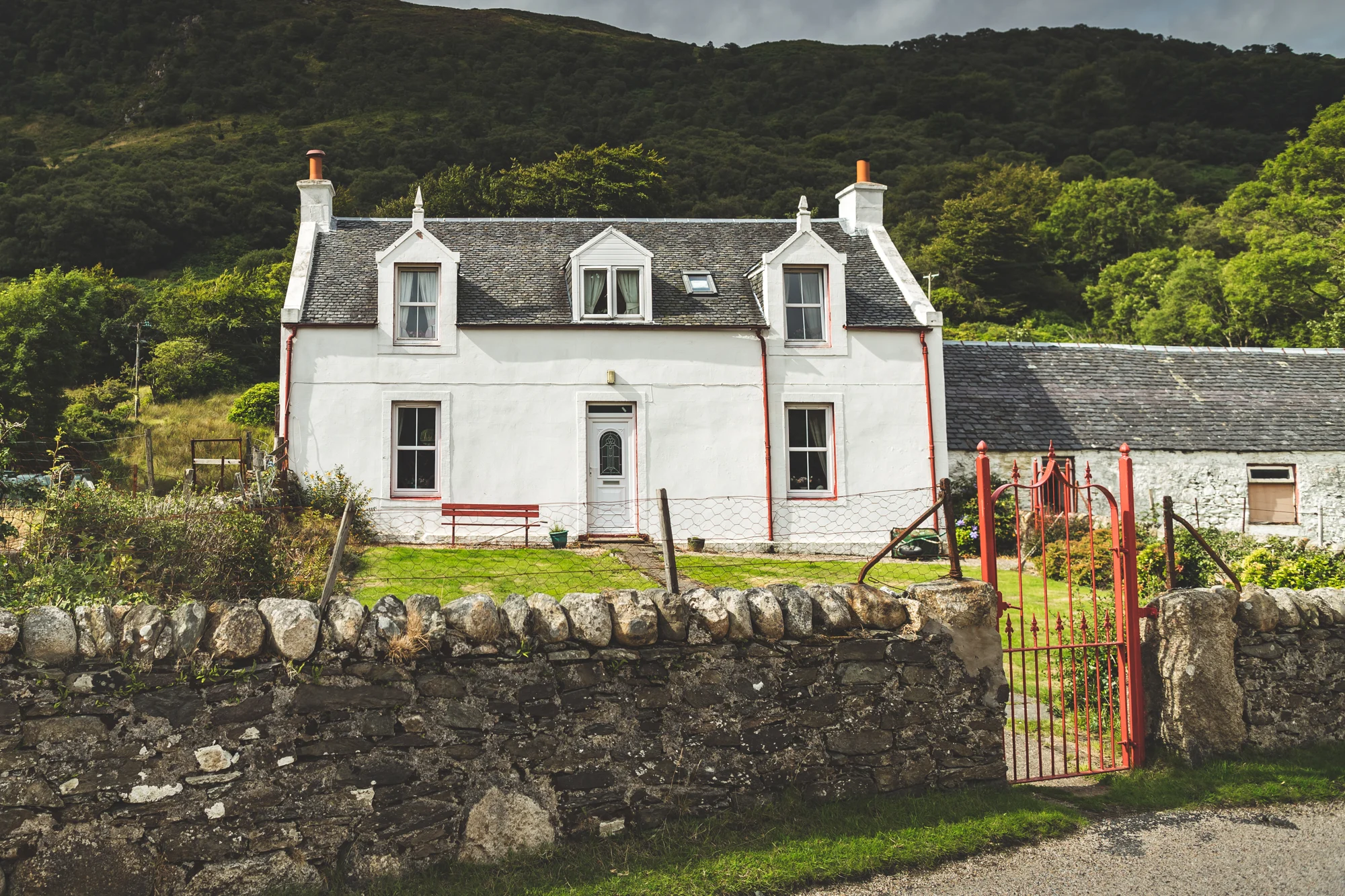 White Irish country house framed by stone walls and green hills